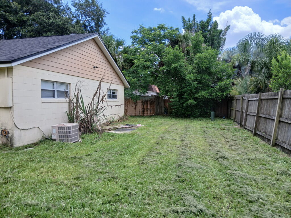 After residential yard mowing with freshly cut grass beside a Central Florida home