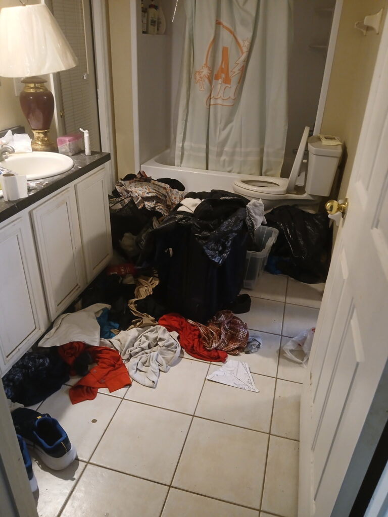 Before bathroom cleaning and organization with clothing and clutter on the floor