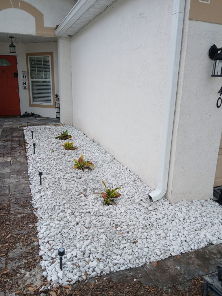 After decorative rock landscaping with white rock and small plants near the front entry