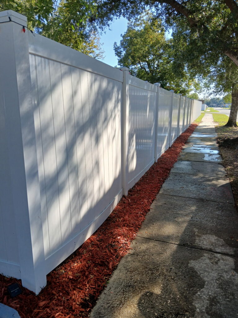 Fresh mulch and exterior cleanup along a white fence beside a walkway
