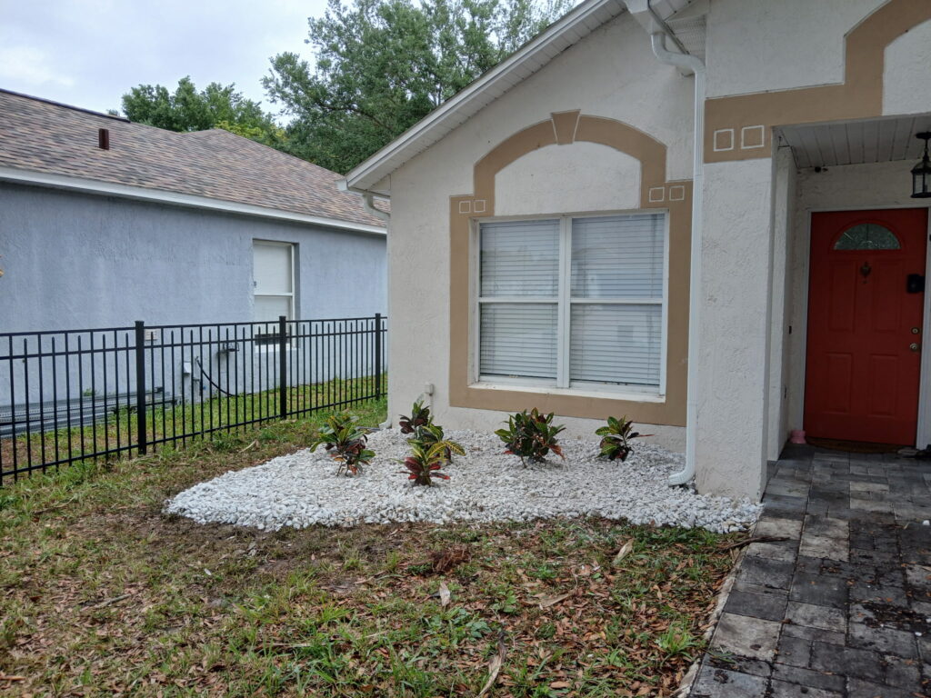 Front rock landscaping refresh with white decorative rock and small plants near the entry